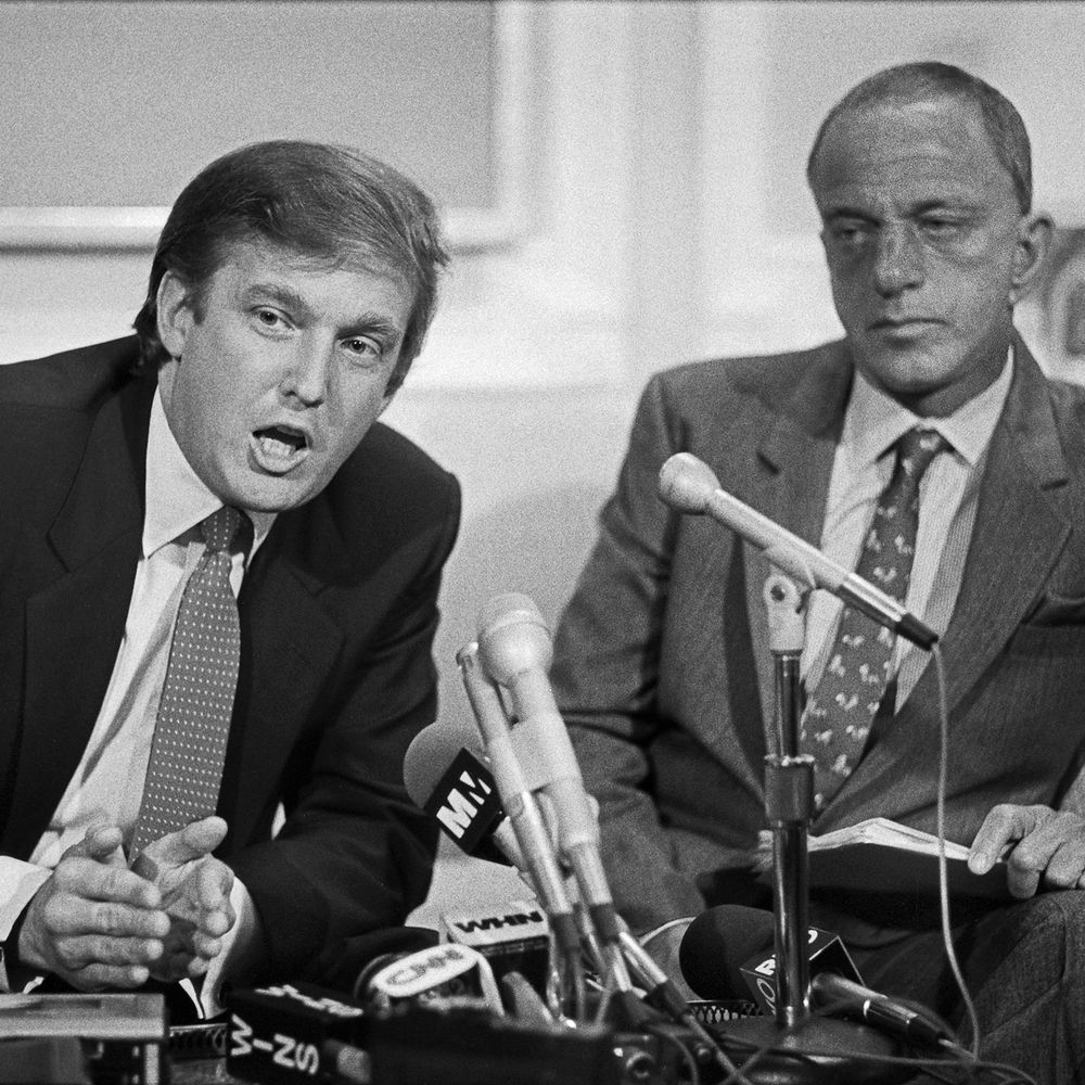 Roy Cohn sitting beside (younger) Trump during a press conference.