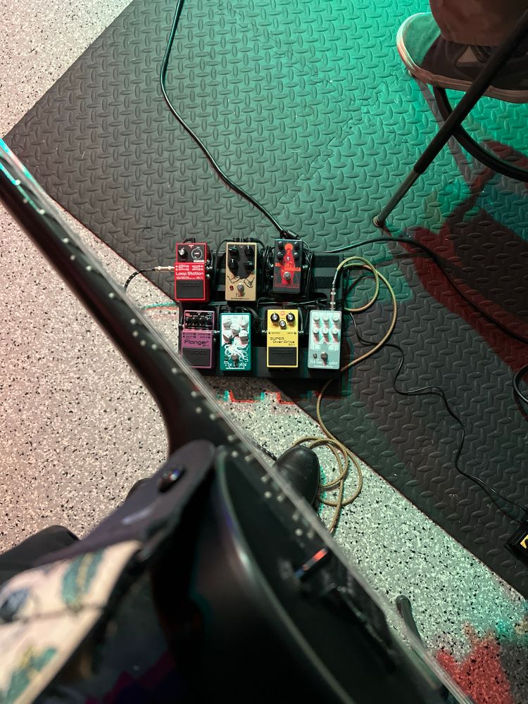 A picture of an electric guitar over several guitar pedals