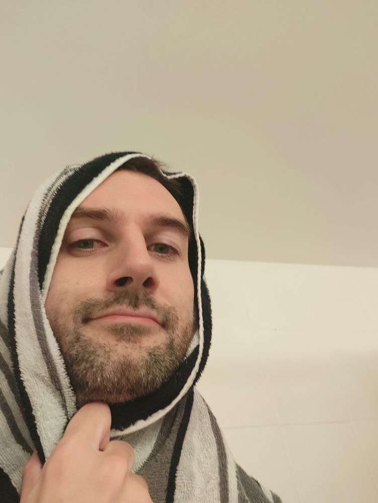 A homosexual drying off after a warm shower on a very cold day using his towel to keep his head warm 