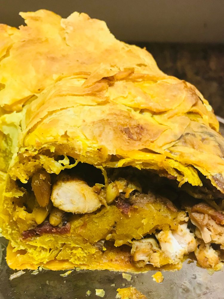 A close up of flaky phyllo pastry filled with chunks of chicken, squash, and bacon