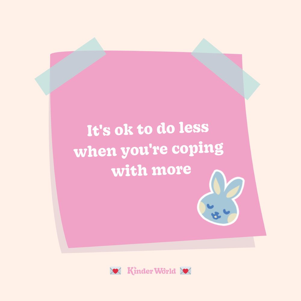 A pink post-it note, stuck onto a beige background with pastel blue tape, with the text 'It's ok to do less when you're coping with more'. In the bottom right-hand corner there is a kawaii paste blue bunny, with yellow cheeks and a soft expression.