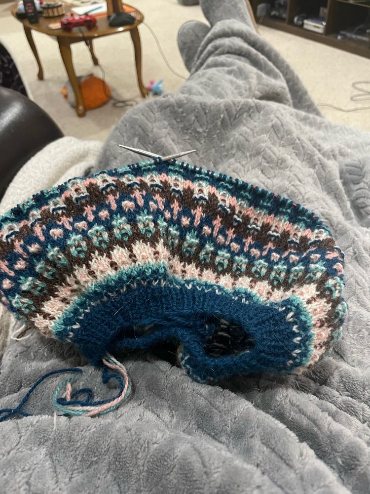 Work in progress knitted colorwork on top of a cozy blanket
