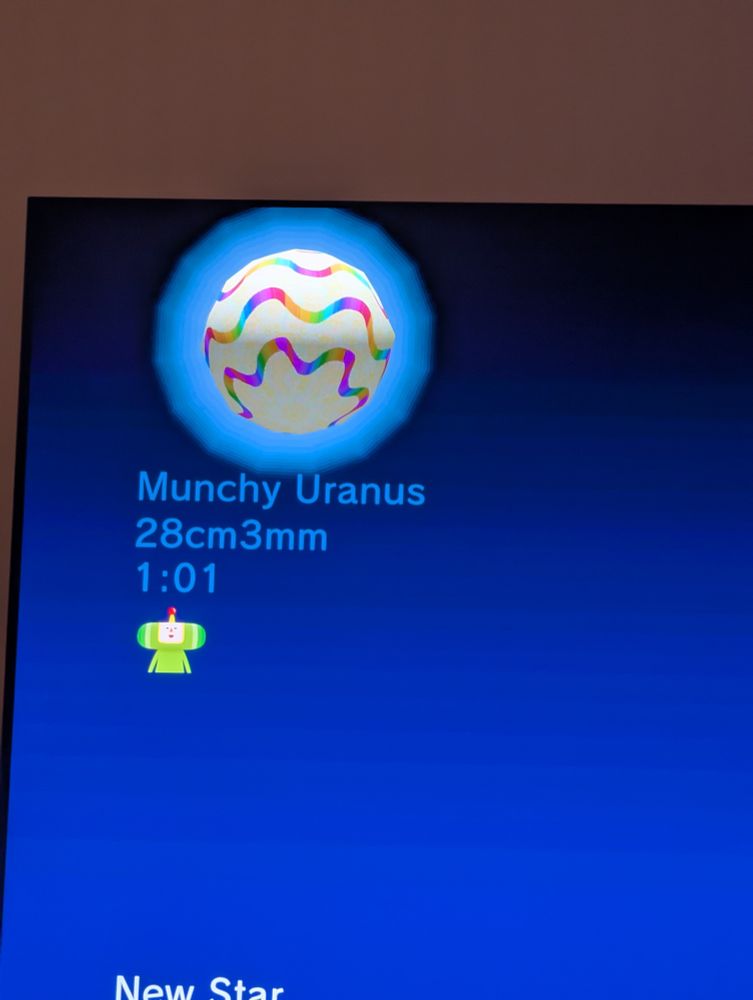 A screenshot of the score screen from We Love Katamari. It shows a white planet with wavy rainbow bands. It is labeled "Munchy Uranus" and is 28cm 3mm large, took me 1:01 to get to that size. You can see a little bit of The Prince under the score.