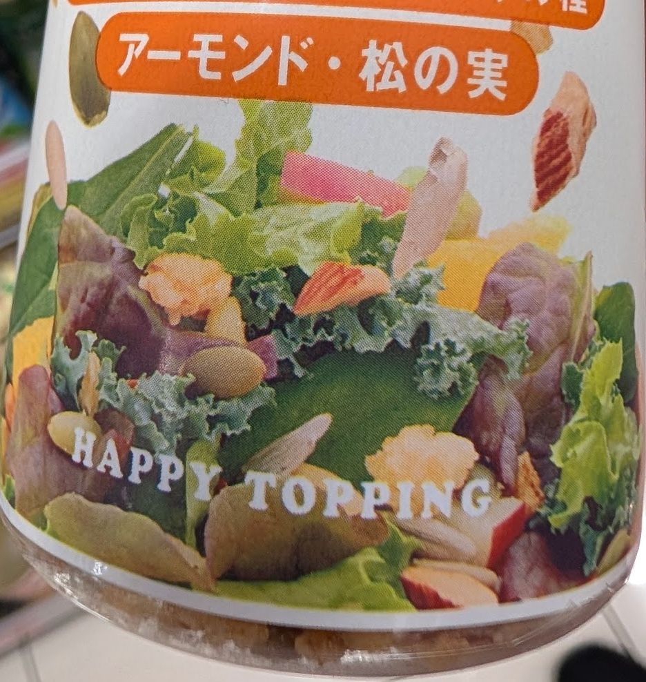 A close-up of a bottle of Japanese salad dressing. In English, at the bottom, it reads "happy topping"