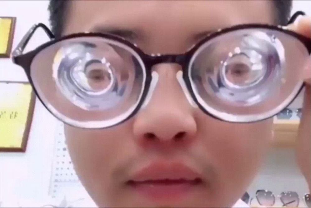 a close up of a person 's face wearing glasses with a large lens