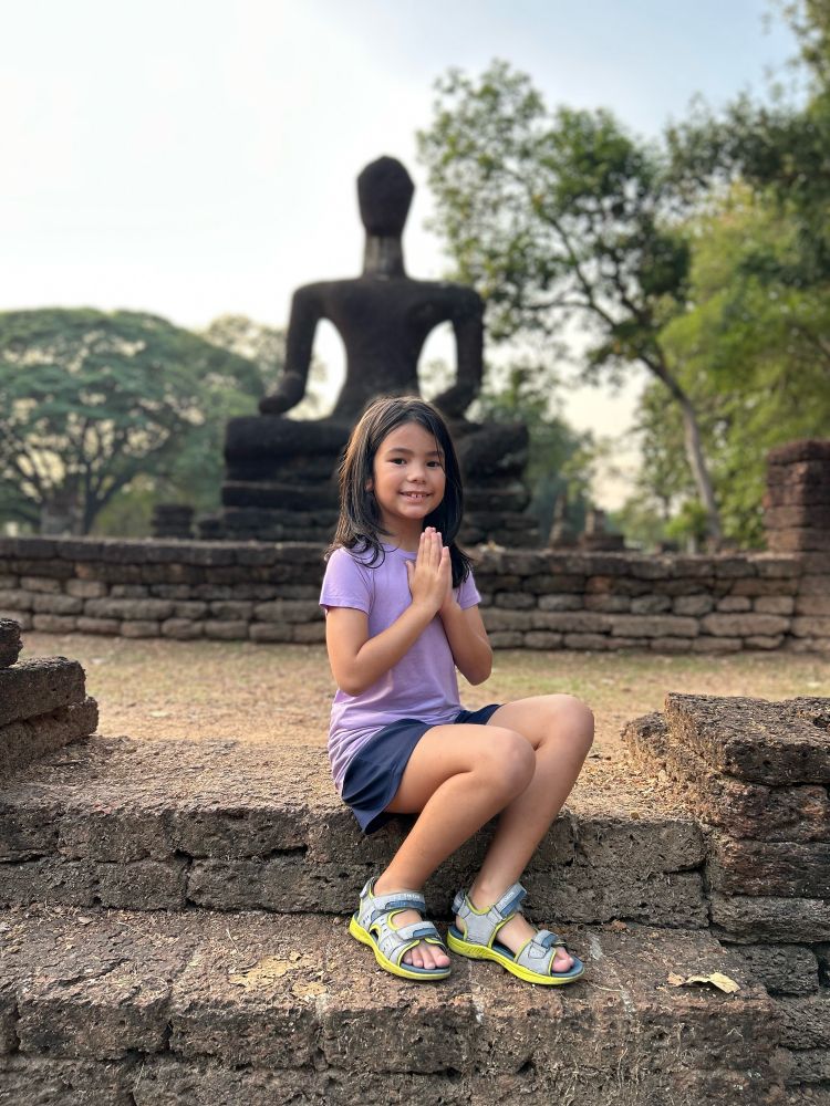 Wat Singha Buddha and a little girl doing the traditional Thai wai. 