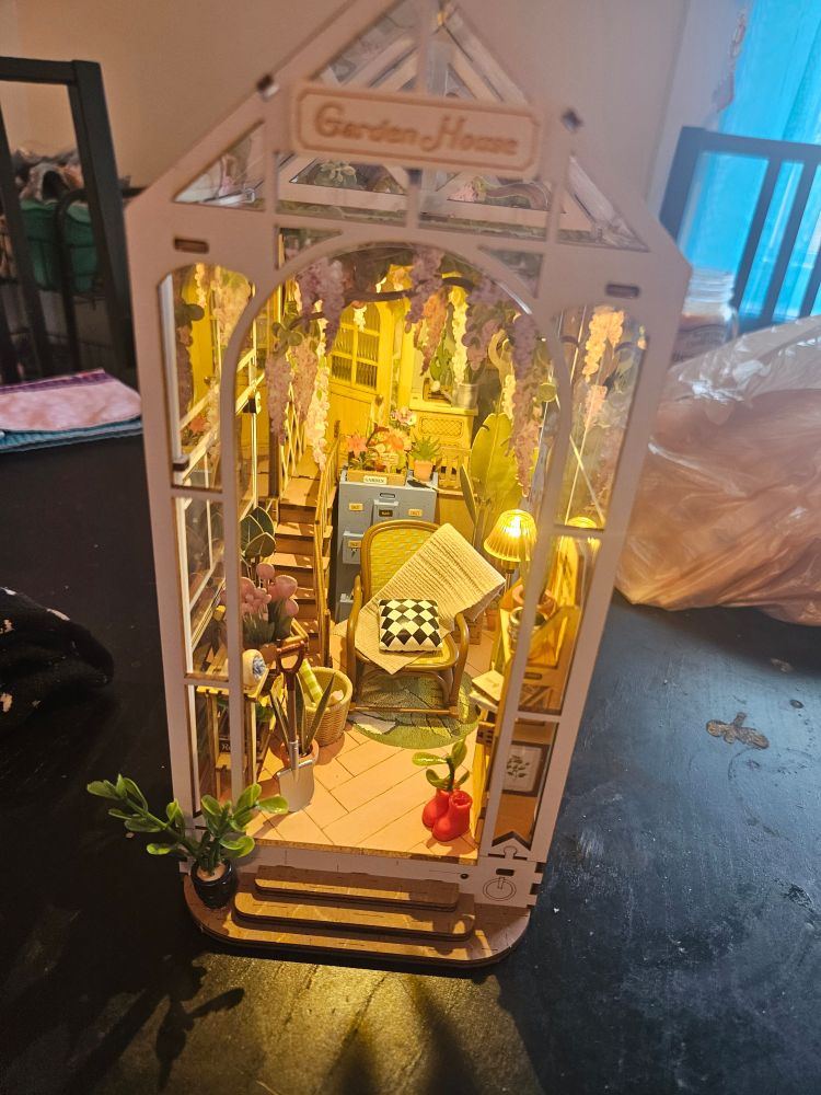 Picture of an assembled book nook that is a Garden House with plants, tiny furniture, and stairs into a second level.