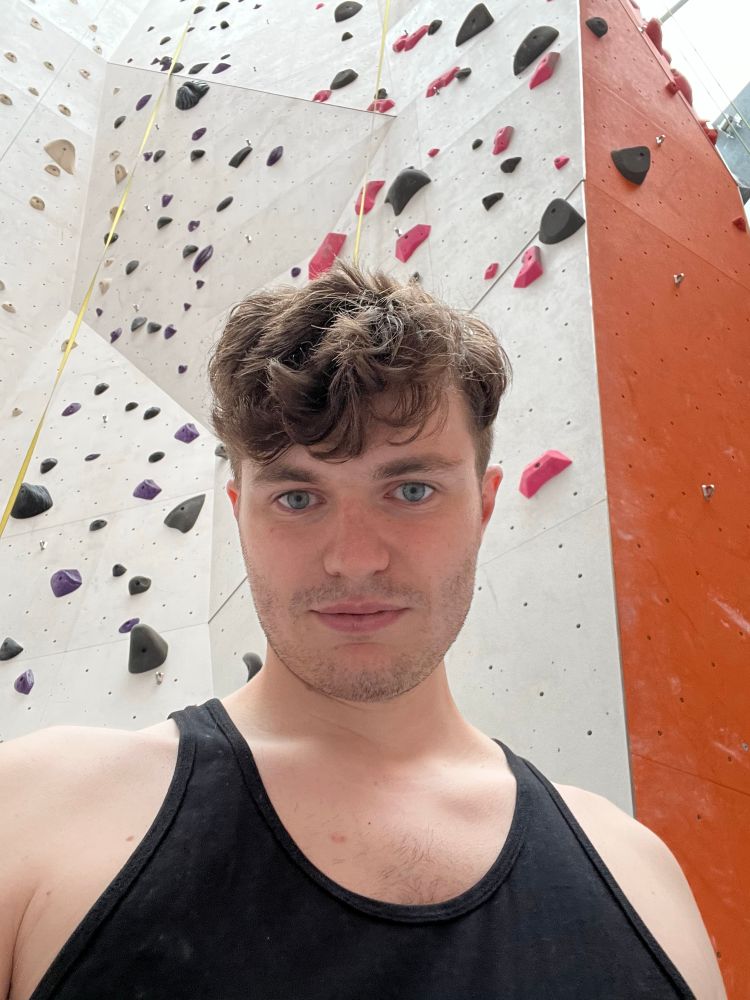 Selfie of a man wearing a tank top in a climbing gym