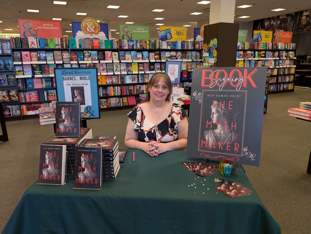 Photo of author Alie Dumas-Heidt sitting at a table at a Barnes & Noble bookstore. 