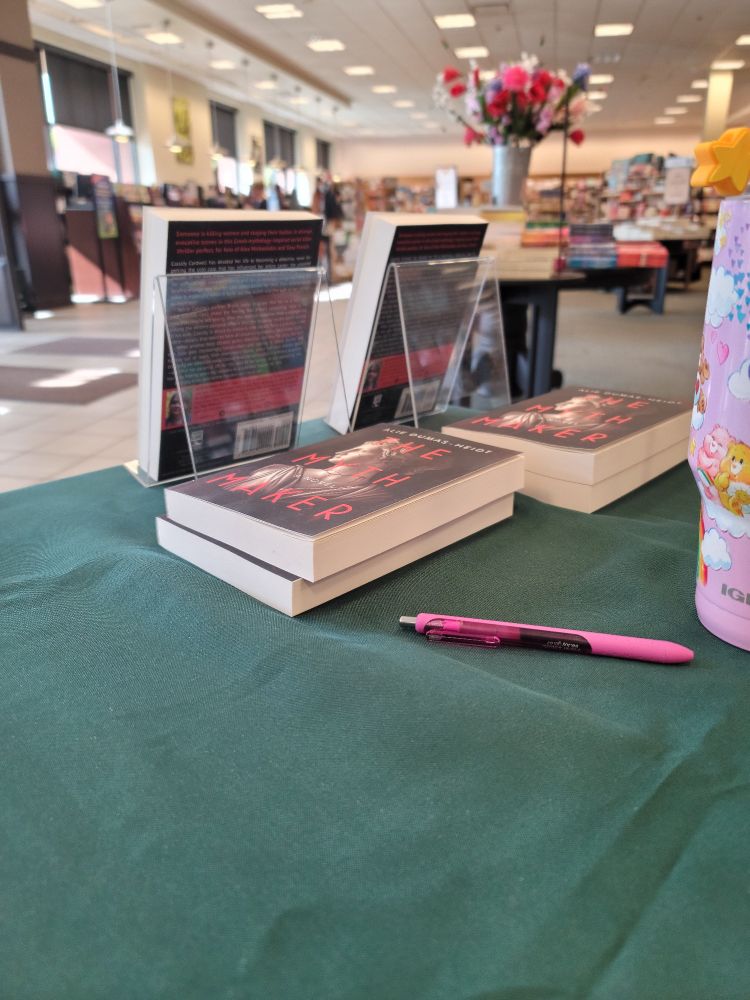 A small stack of books and a pink pen on a table. 