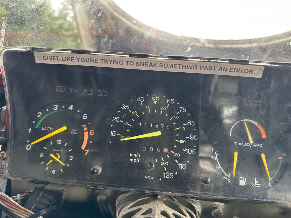 A sticker that says “shift like you’re trying to sneak something past an editor” on the dash of a car