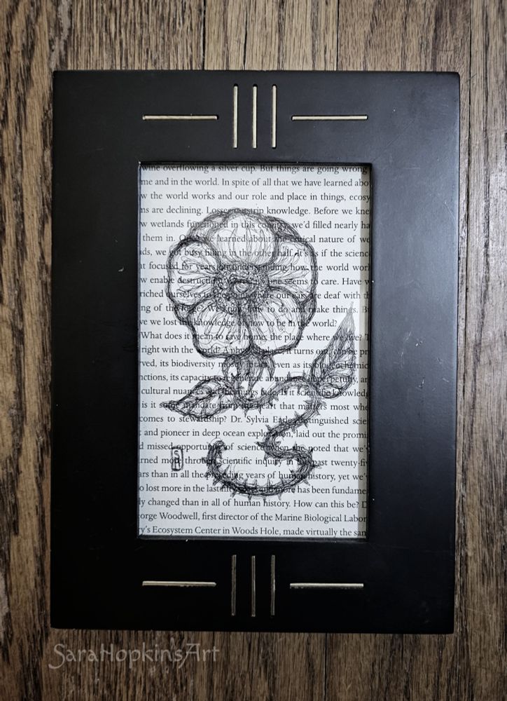 Botanical horror ink illustration of flower with eye drawn on upcycled book page. Set in vintage art deco frame. 