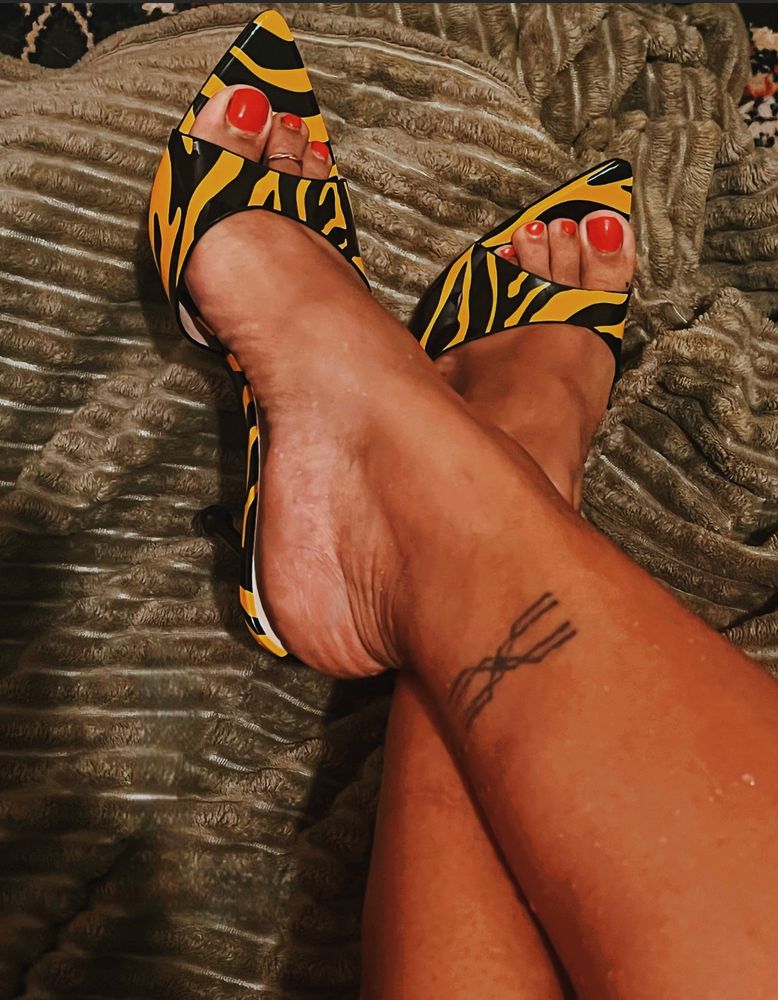 Yellow and Black zebra striped heels on a black woman with cherry red nail polish 