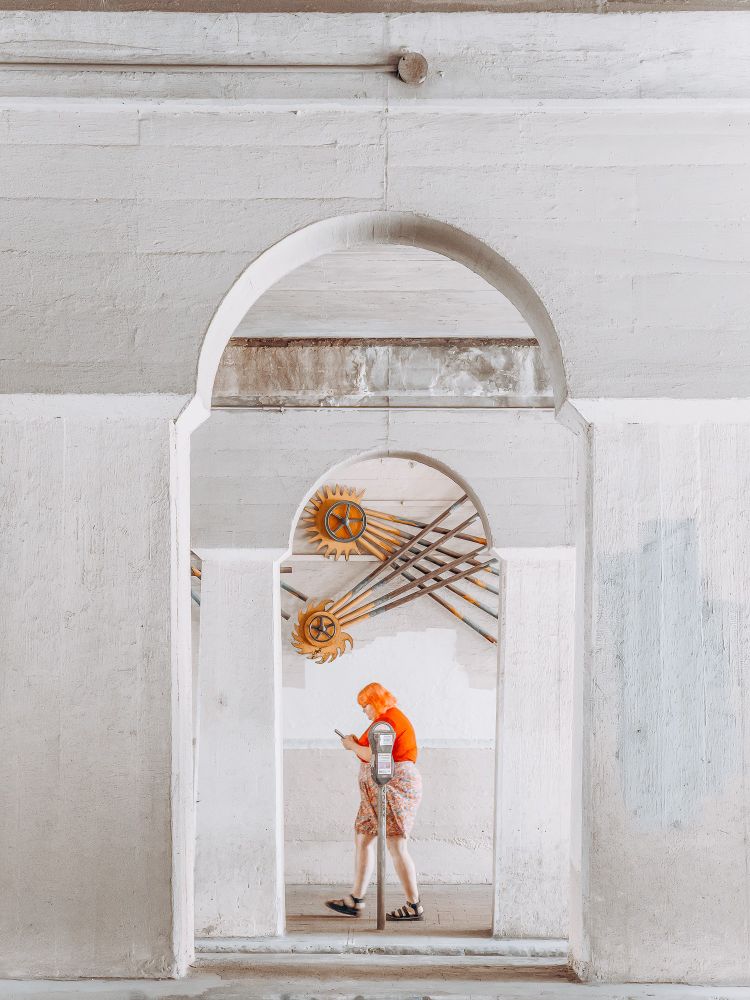 Profile shot of woman walking under train trestle.