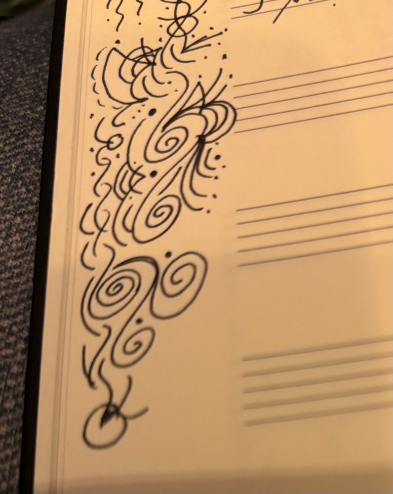 Music manuscript paper with some swirly doodles drawn in the margin