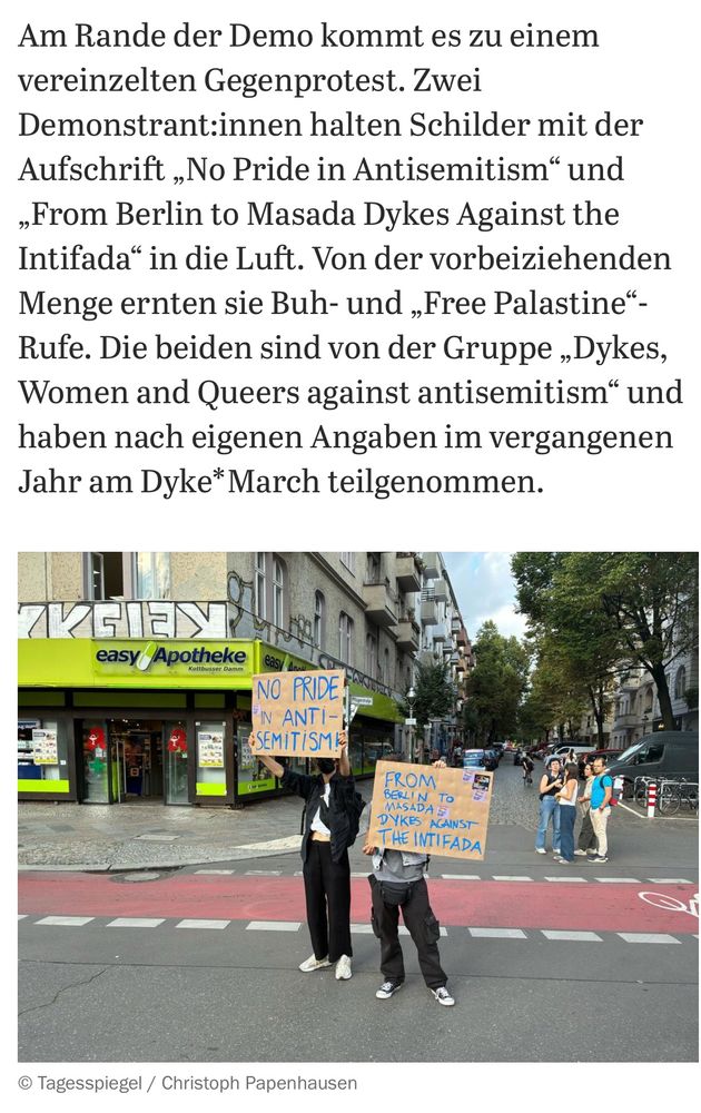 Zwei Demonstrant:innen halten Schilder mit der Aufschrift „No Pride in Antisemitism“ und „From Berlin to Masada Dykes Against the Intifada“ in die Luft. Bild aus dem Tagesspiegel.