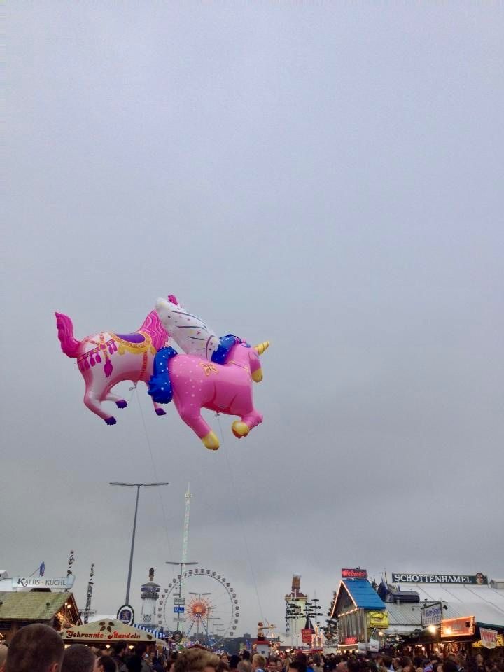 Zwei pinke Einhörner Ballons schweben über dem Oktoberfest.