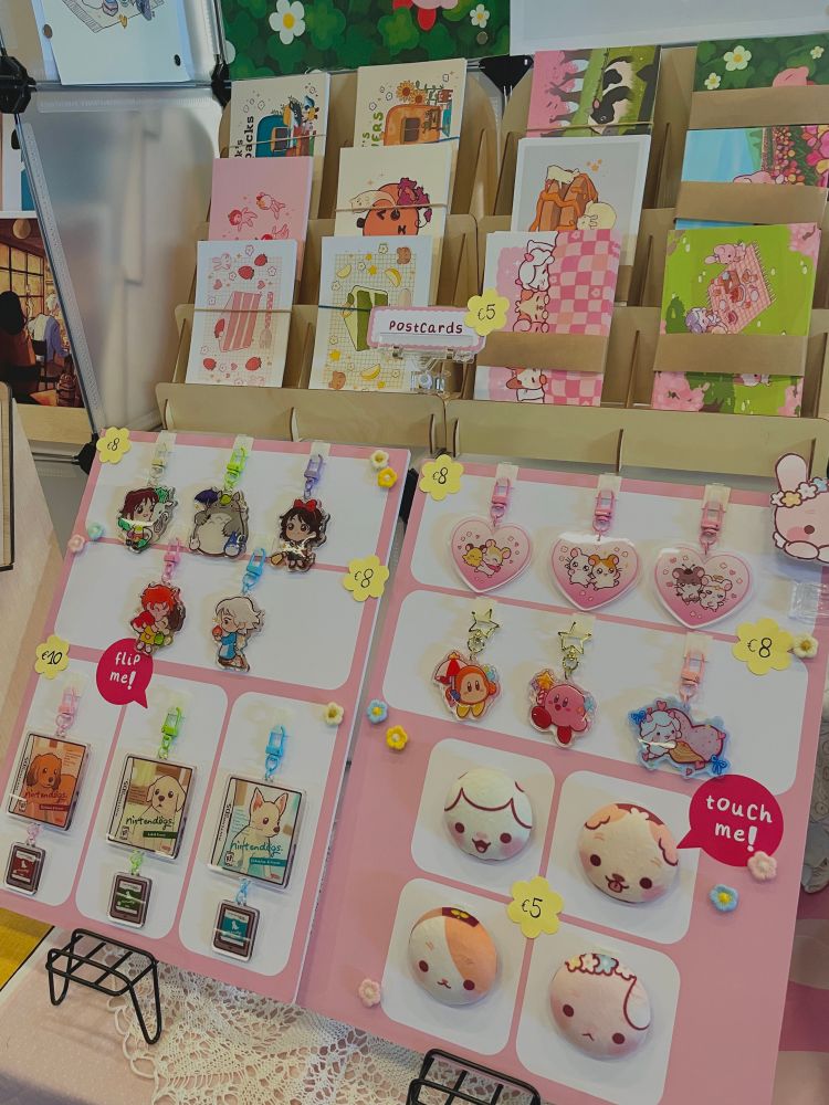 A close-up of the booth. Displayed are charms, buttons and postcards.