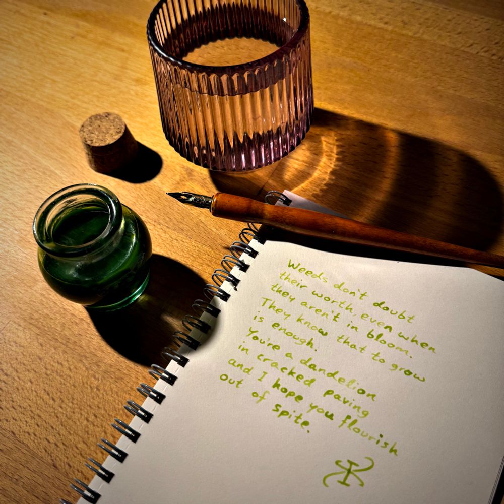 The same poem in a notebook, with a dip pen, a glass of water, and a pot of deep green chlorophyll ink. 