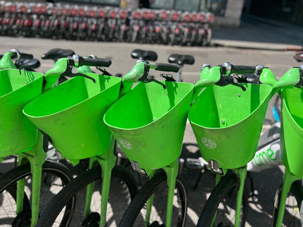 Close up of the green baskets on a row of parked Lime bikes in central London. 