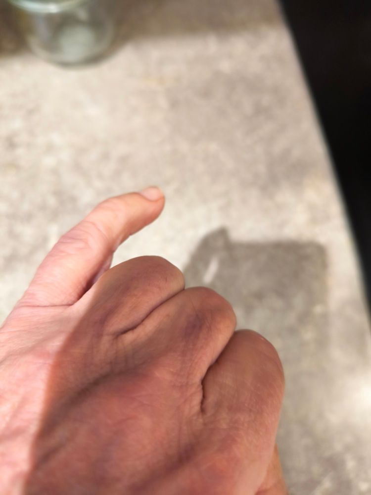 Une main avec les doigts pliés et l'auriculaire tendu. 