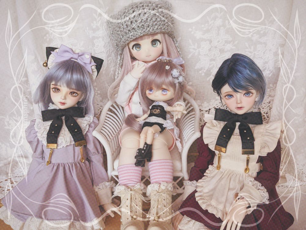 edited photo of a group of dolls with a slight sepia-tone to it.
left: blue haired doll with blue wig, wearing a purple dress and black bow
middle: pink haired doll wearing a knitted beanie sitting in a white chair, with a smaller pink haired doll sitting in its lap
right: short blue haired doll wearing a similar dress and bow as left, but red and with a white apron