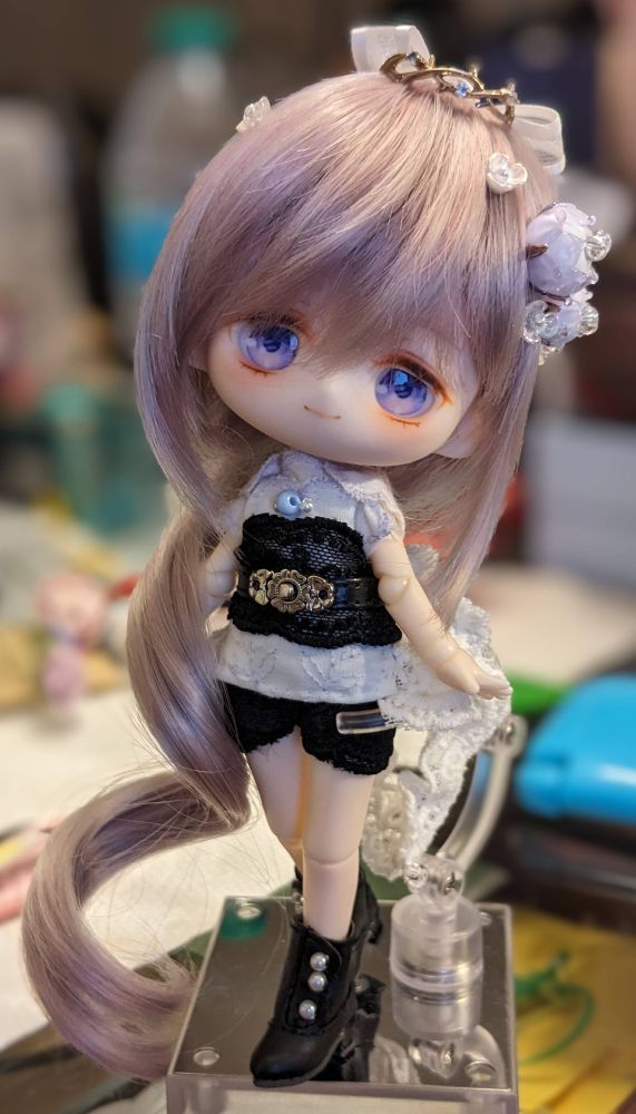 11cm doll with purple/pink hair and eyes, wearing a light purple and black outfit with black shoes