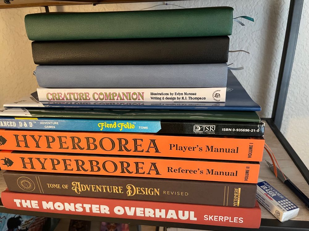 Hyperborea by Jeff Talanian; The Monster Overhaul by Skerples; The Matt Finch Bible (AKA Tome of Adventure Design); AD&D Fiend Folio; D30 sandbox and DM companion’s by Richard LeBlanc; Creature Companion by RJ Thompson, fully illustrated by Evlyn Moreau; notebooks, pencil, eraser, and miscellaneous