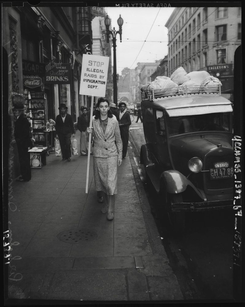 true buckaroo holding a sign that says 'stop illegal raids by immigration dept' taken in 1940