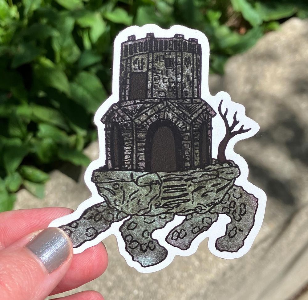A photo of a sticker of the walking mausoleum from Elden Ring. It looks like it’s doing a little dance.