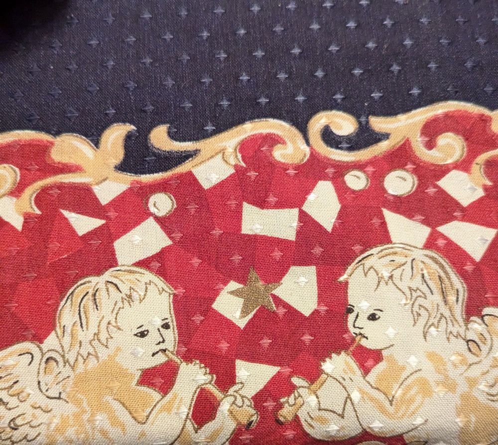 Zwei Putten abgebildet auf einer Tischdecke, sie spielen Flöte und gucken dabei etwas traurig