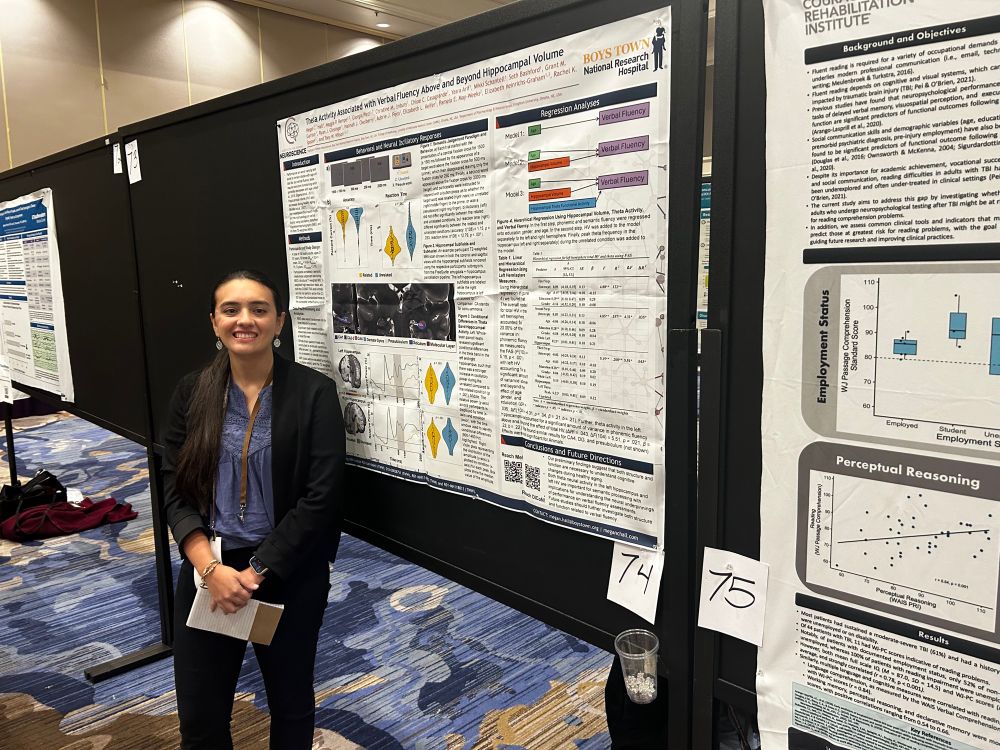 A young woman in a blue shirt standing next to a scientific poster