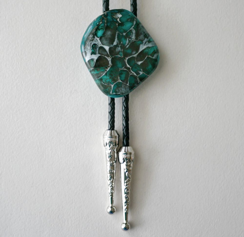 teal, grey and white bolo tie with a pattern resembling reptilian scales. the shape is irregular, rounded, organic