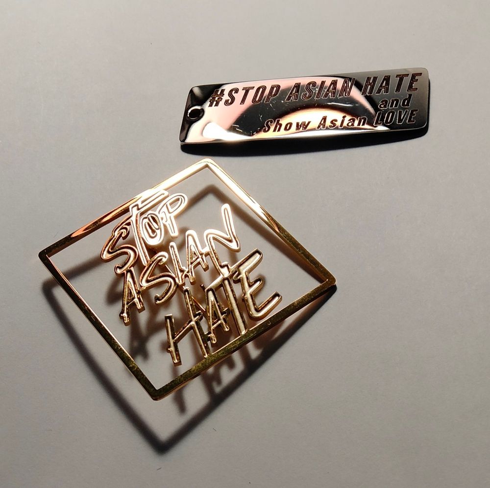 #StopAsianHate and Show Asian Love の文字が刻印されたプレートハガネ。stop asian hateの文字の形の金色のピン