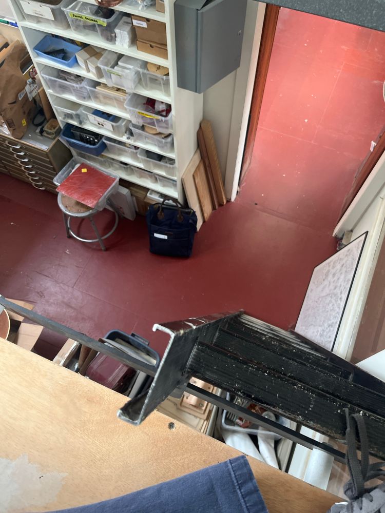 A view down from an approximately 10 foot tall lofted space to an office with a red floor. 