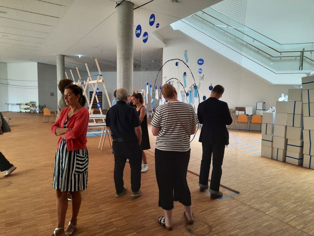 Einige Tagunsteilnehmer:innen betrachten eine kleine Sonderausstellung/Intervention im Leibniz-Zentrum für Archäologie (LEIZA), unserem Tagungsort.