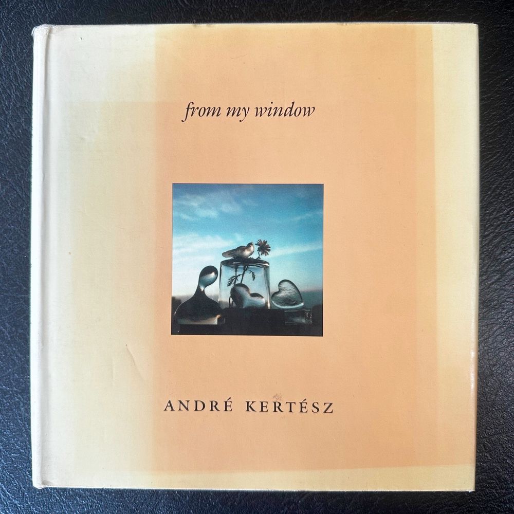 Front cover of a book of photos by Hungarian-American artist André Kertész. Glass ornaments on a windowsill refract the light from the New York sky beyond.