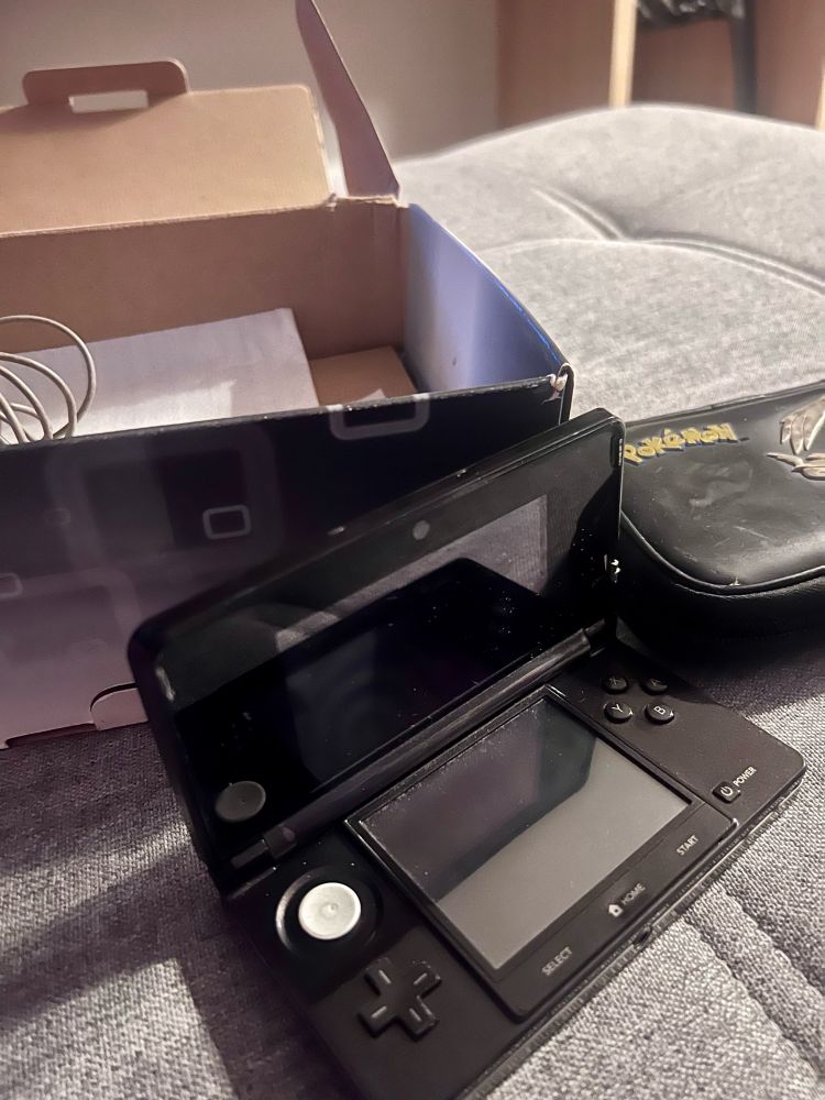 Na foto temos um Nintendo 3s junto com a caixa e o estojo para guardar.