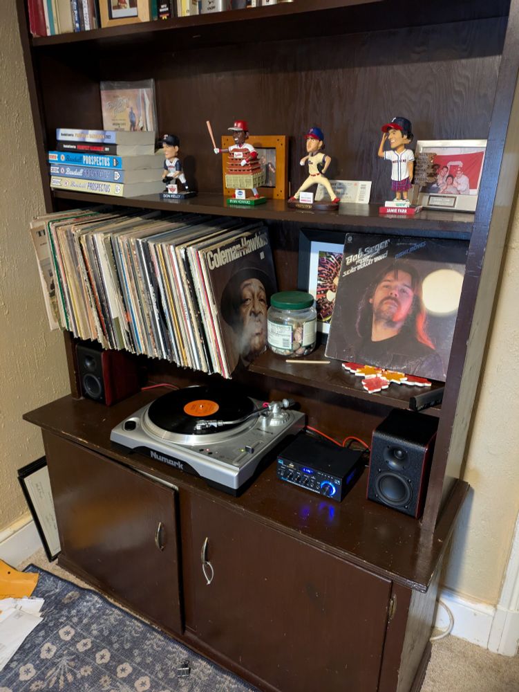A turntable on a bookshelf playing Night Moves by  Bob Seger.