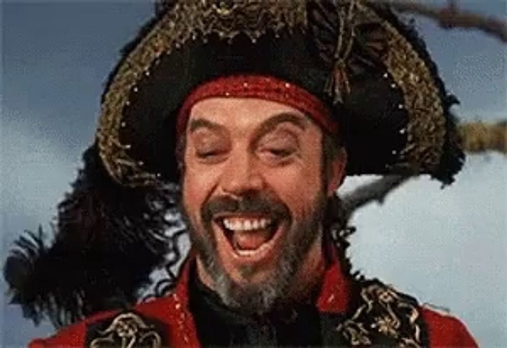 a man with a beard is wearing a pirate costume and smiling .