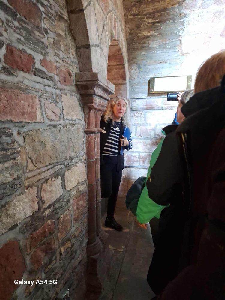 A person in a striped jumper standing in a stone archway. 