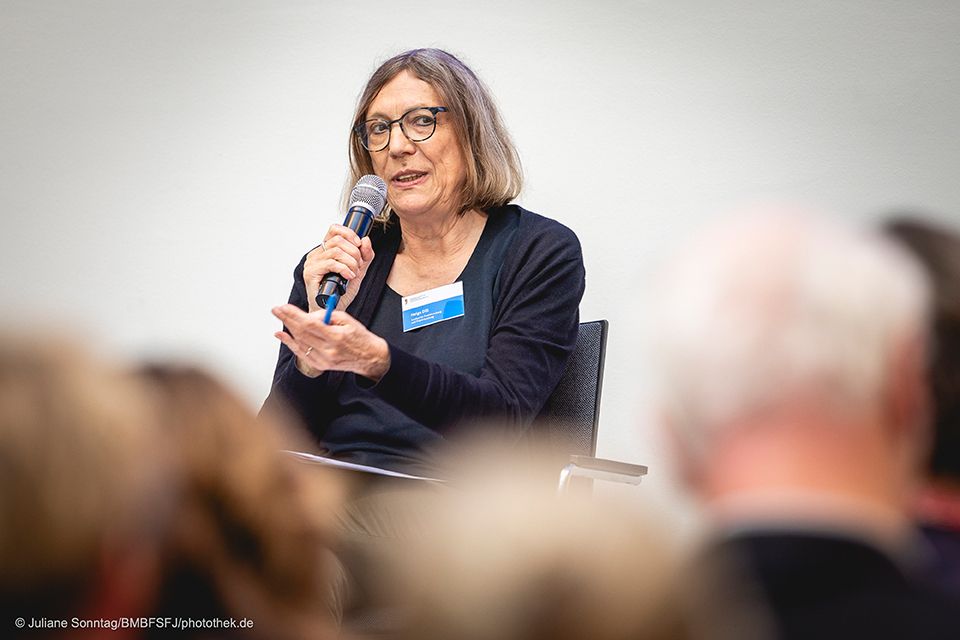 Foto Helga Dill auf der Bühne, sitzend, mit Mikrofon