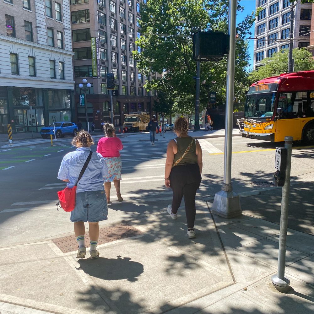 People walk at 3rd Ave and Yesler Way, a site of recent improvements to make walking, rolling, biking, and traveling in the area simpler and safer.