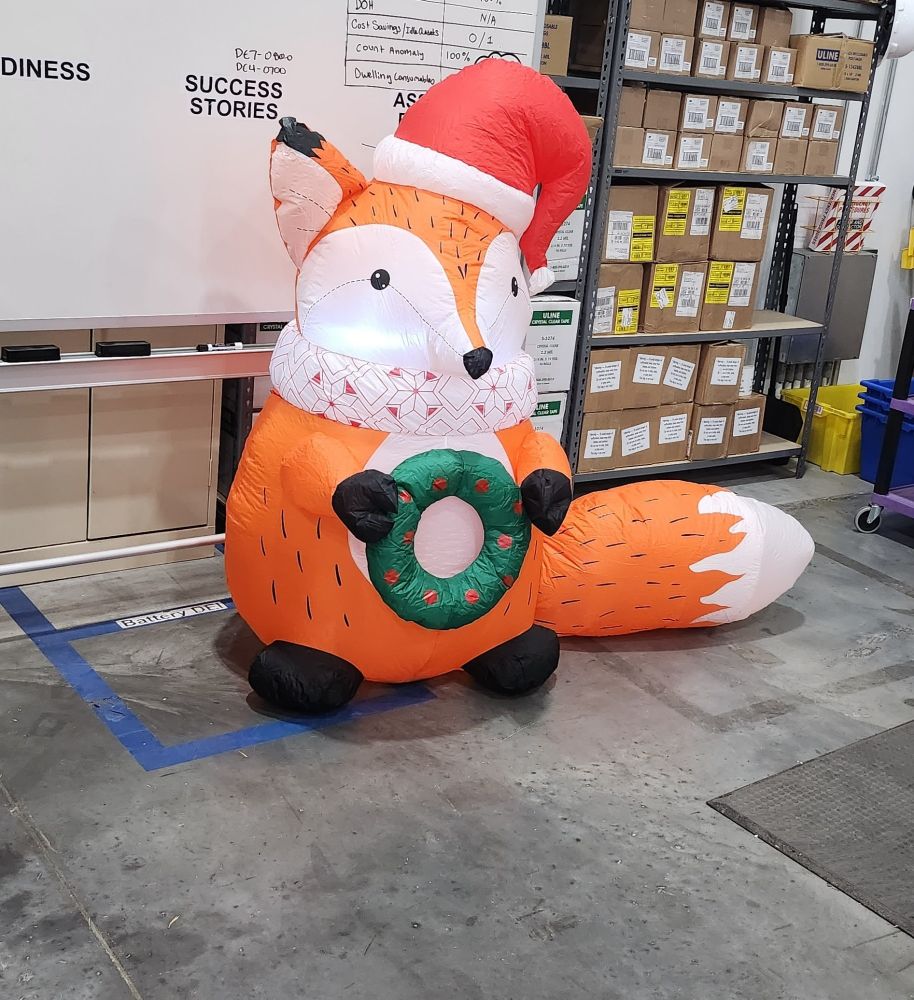 A 5 foot (1.524m) inflatable fox in front of a portable whiteboard in a warehouse setting