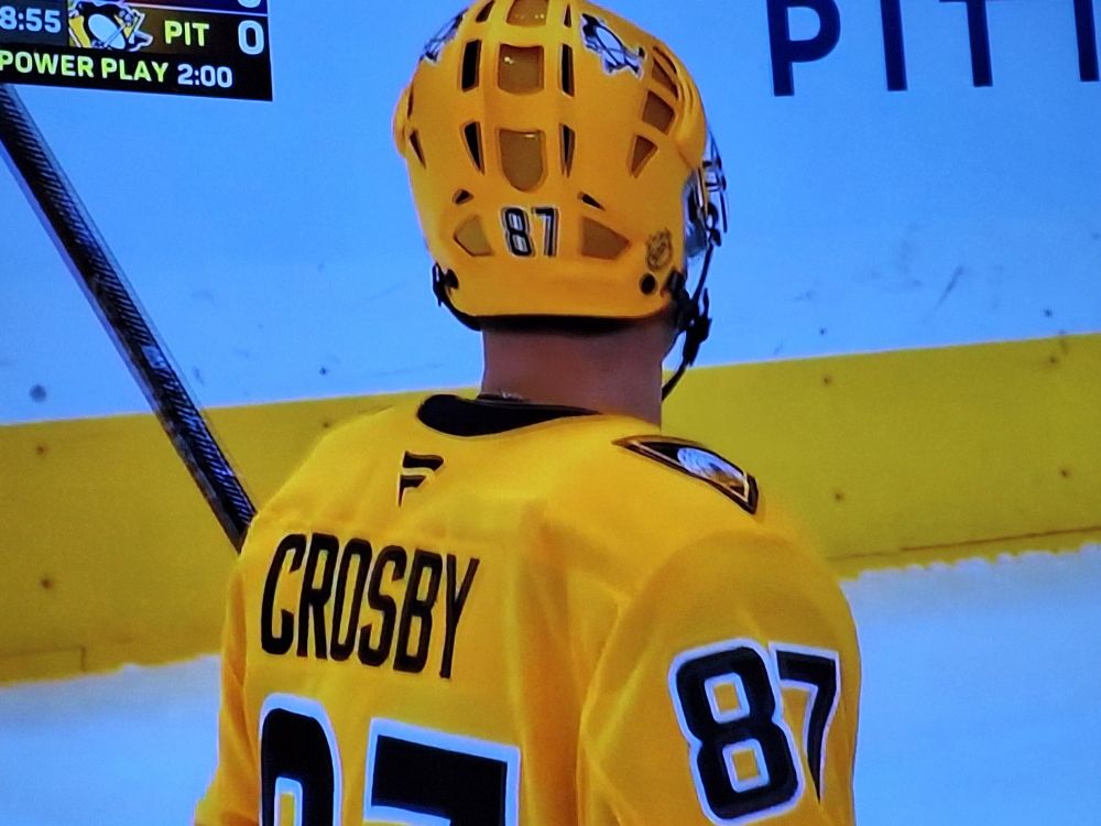 Sidney Crosby wearing a bright yellow hockey sweater and helmet 