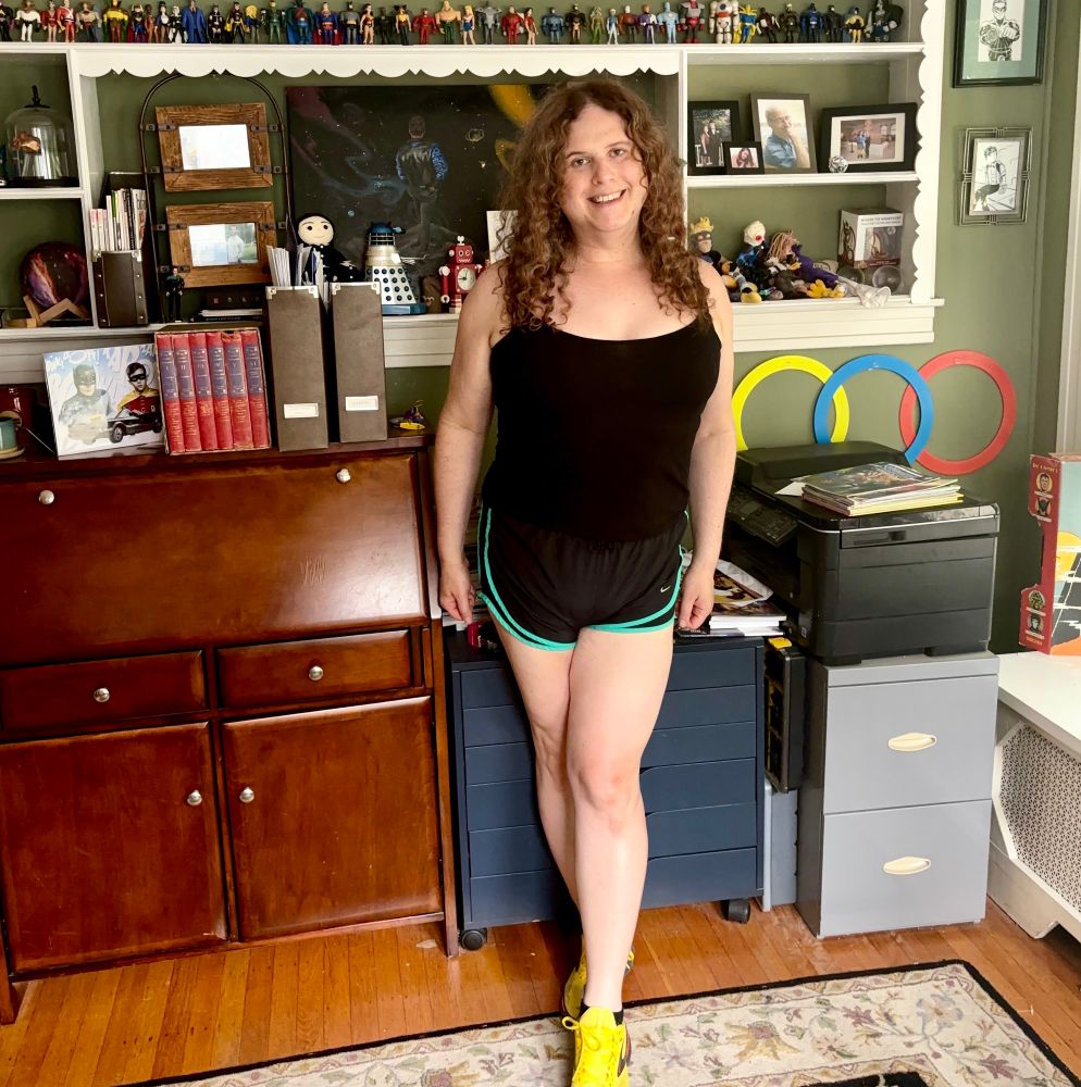Jadzia is wearing a black tank top, black running shorts with green trim, black ankle socks and yellow Brooks running soes
