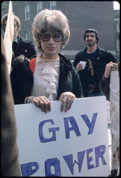 Sylvia Rivera in the early 1970s, holding a sign that says "GAY POWER"