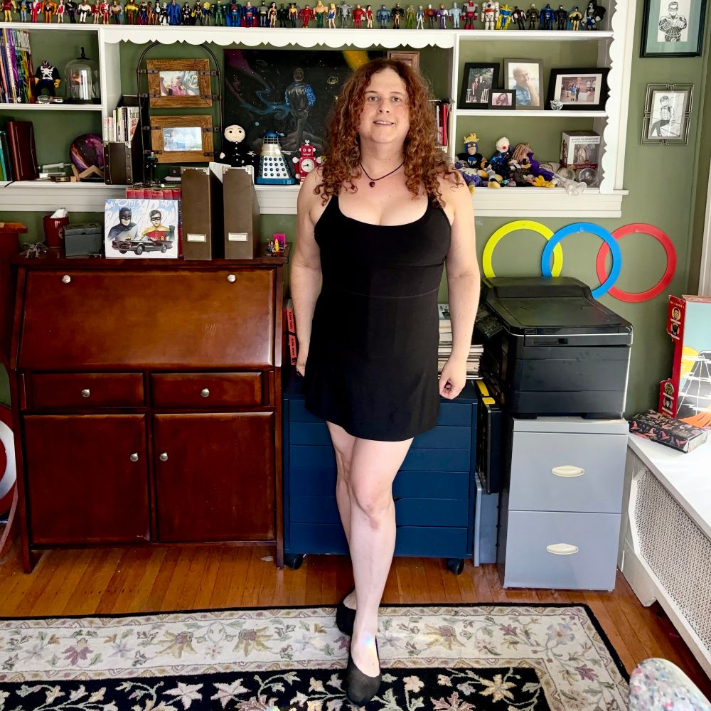 Jadzia is wearing a necklace with a small carnelian heart-shaped pendant, a short black athletic dress and black Sketchers ballet flats.