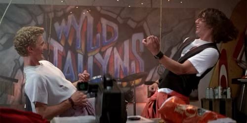 Still from a Bill &Ted’s movie with the name of their band. “Wyld Stallions” spray painted on a wall