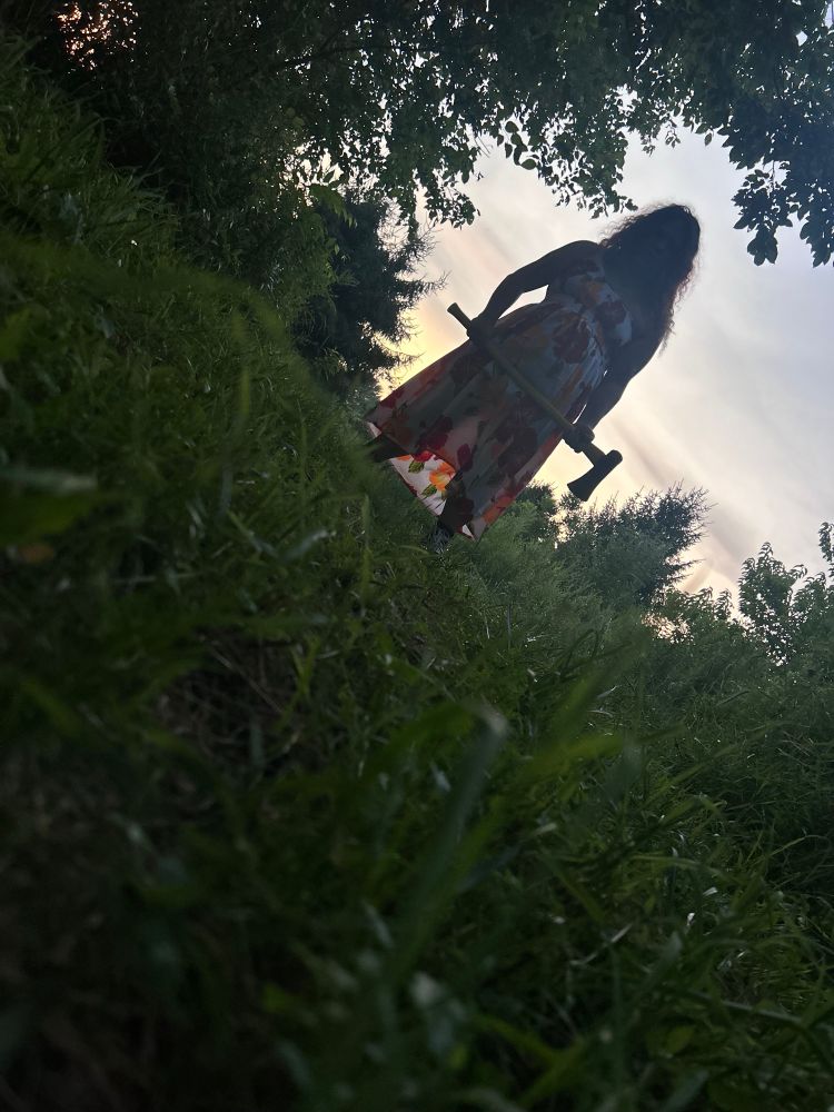 Kamille holding an axe, silhouetted by a distant sunset 